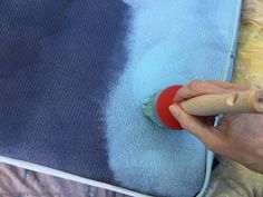 someone using a brush to paint a blue and white blanket