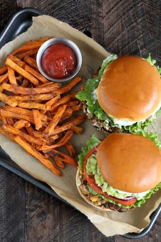 two hamburgers and fries on a tray with ketchup