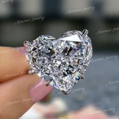 a heart shaped diamond being held by someone's hand in front of the camera