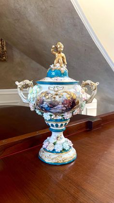 a blue and white vase sitting on top of a wooden table next to a stair case