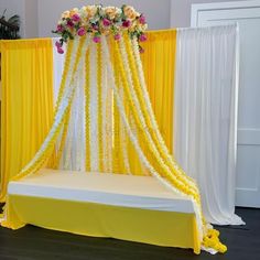 a yellow and white wedding setup with flowers on the headboard, draping and curtains