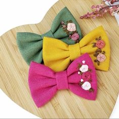 three bow ties with flowers on them are sitting on a wooden table next to a vase