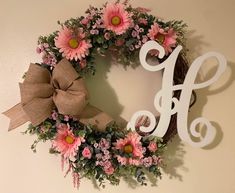 a wreath that has the letter h on it and some flowers in front of it