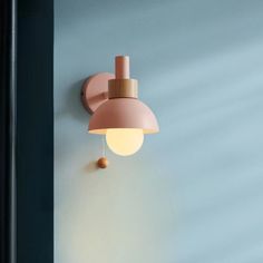 a pink wall light mounted on the side of a blue wall