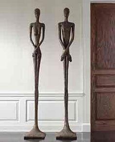 two statues are standing next to each other in front of an open door and another one is sitting on the floor