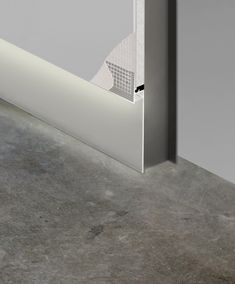 the corner of a wall with a white door handle on it and a grey floor