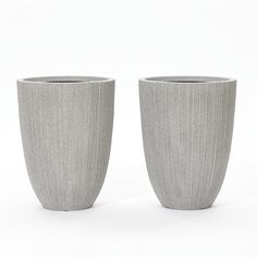 two gray vases sitting next to each other on a white surface with no one in it