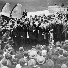 an old black and white photo of people standing in front of a plane