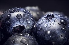 blueberries with water droplets on them are shown in this close up photo, which appears to be dark