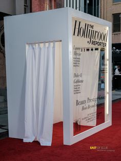 the hollywood reporter booth is set up on red carpeted area with white walls and curtains