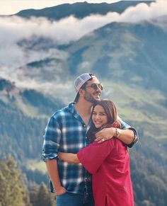 a man and woman embracing each other in the mountains