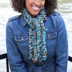 a woman with curly hair wearing a blue jean jacket and a crocheted scarf