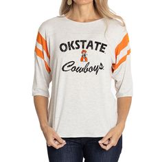 Elevate the style of your game day tee with this Oklahoma State Cowboys Sabrina Jersey T-shirt. It features the team name and logo accentuated by contrast-color side stitching and sleeve stripes. A rounded hem gives this Oklahoma State Cowboys shirt a more comfortable fit and feel. Game Day Jersey Tops For Baseball Season, College Jersey Tops With Team Logo, Varsity Jersey T-shirt For Game Day, College Team Logo Jersey Tops, Collegiate Game Day T-shirt With Team Name, Varsity Jersey T-shirt For Baseball Season, Varsity Jersey T-shirt With Team Logo, Varsity Team Logo Jersey T-shirt, Varsity Logo Print T-shirt For Game Day