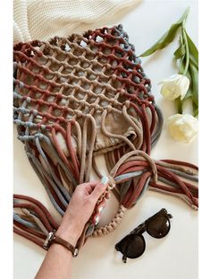 a woman's hand is holding a piece of fabric next to sunglasses and flowers