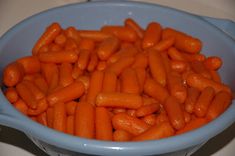 a blue bowl filled with baby carrots on top of a counter