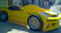 a yellow car shaped bed sitting on the side of a road next to a building