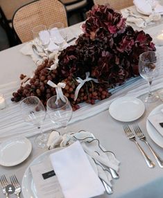 the table is set with white and silverware, napkins, and place settings