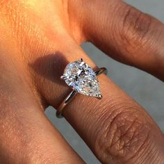 a woman's hand with a diamond ring on her left hand and the other hand holding an engagement ring