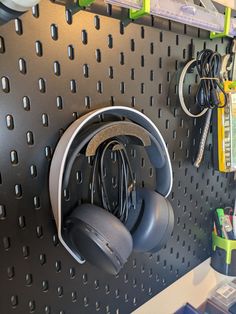 several headphones hanging on a peg board