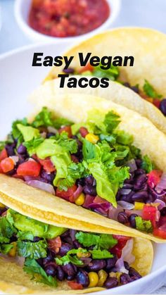 three tacos filled with beans, lettuce and salsa on a white plate