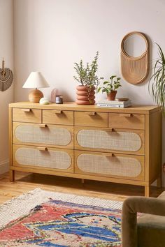 a wooden dresser with baskets on top and plants in the bottom drawer next to it