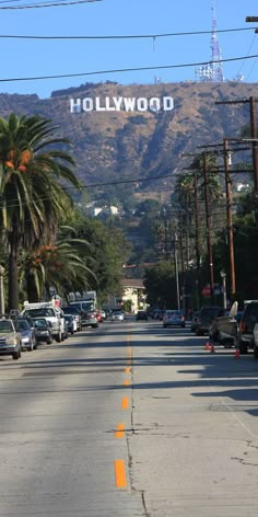 cars parked on the side of a road with hollywood sign in the background