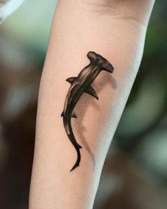 a black and white photo of a dolphin tattoo on the arm