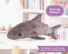 a stuffed shark laying on top of a table next to a book shelf filled with books