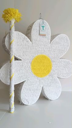 a white and yellow flower shaped object next to a stick with a tag on it