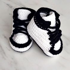 two crocheted baby shoes sitting on top of a white counter next to each other