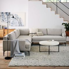 a living room filled with furniture and a stair case in front of a white wall