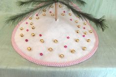 a small christmas tree decoration on top of a white table cloth covered with pink and gold ornaments