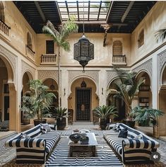 an indoor courtyard with striped couches and potted palm trees in the center area