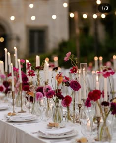 the table is set with candles and flowers in vases, plates and napkins