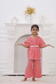 Our Girls Kaftan Set is a must-have for your Girls. Made with 100% pure cotton cambric, this Kaftan Set is quite soft and tactile to touch making it a perfect match for your small one. Traditional print in pretty colours makes this kurta look distinctively good while wearing it. Composition: 100% cotton cambric The Kaftan Set is a gorgeous set of two pieces, includes a white cotton lace on Kaftan sleeves, Kaftan flare & pant bottom. The elasticated kaftan with a belt & loop for belt and elasticized pants to match, it has a button at the back that can be made secure or open, as you wish! Wash care : Hand wash separately in cold water. Use mild detergent. Dry in shade. Summer Pink Cotton Palazzo Set, Festive Short Sleeve Cotton Kurta, Festive Cotton Kurta With Short Sleeves, Festive Cotton Frock, Cotton Frock For Festive Occasions, Red Cotton Palazzo Set, Pink Cotton Dress For Navratri, Red Cotton Dress For Diwali, Red Cotton Diwali Dress