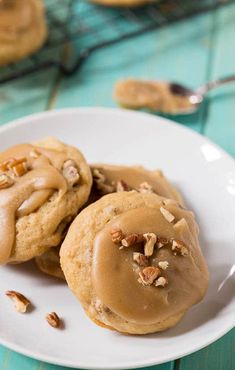 three cookies on a plate with peanut butter frosting and pecans in the background