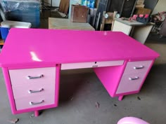 a pink desk with three drawers in a room