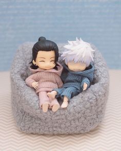 two figurines are sitting in a small bed