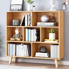 a bookshelf filled with lots of books next to a plant and stuffed animals