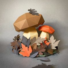 an origami mushroom surrounded by leaves and acorns on a gray background