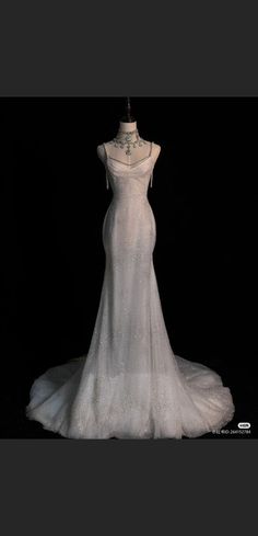 a white wedding dress on display in front of a black background