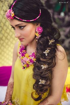 a woman with long hair and flowers in her hair is wearing a yellow dress, holding a