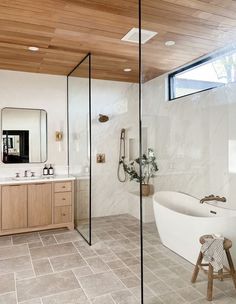 a bathroom with a tub, sink and mirror in it's center wall that has wood paneling on the ceiling