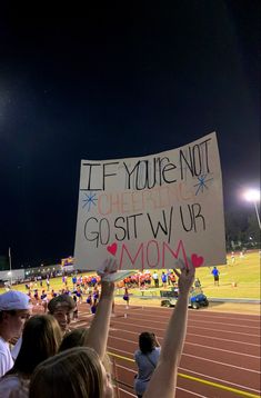 a group of people holding up signs in front of a crowd at a race track