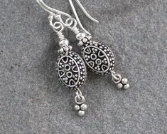 "Oxidized Turkish sterling silver oval beads are accented with coordinating sterling silver charms and securely wire wrapped to sterling silver ear wires. These dainty Bali style earrings are sweet and unique. Perfect to wear everyday. Oxidation may vary slightly for each bead. Total length from the top of the ear wires measures 1 1/2\". Sterling silver is .925 pure silver. Turkish silver is .925 pure silver. Bali silver is .925 pure silver. Check out other items in my shop here: https://www.ets Sterling Silver Teardrop Earrings With Silver Beads, Silver Oval Wire Wrapped Earrings, Oval Silver Wire Wrapped Earrings, Sterling Silver Oval Pendant Earrings In Silver, Handmade Sterling Silver Jewelry With Oval Beads, Sterling Silver Jewelry With Oval Beads For Gifts, Nickel-free Oval Beads Earrings For Gift, Silver Flower Bracelet, Bali Style