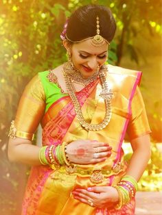 a woman in a yellow and pink sari holding her hands on her chest, looking down