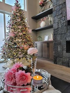 a living room with a christmas tree and flowers on the table in front of it