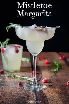 the mistletoe margarita is garnished with rosemary and served in coupe glasses