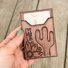 a person holding up a card case with cactus designs on it