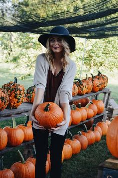 a woman standing in front of a display of pumpkins